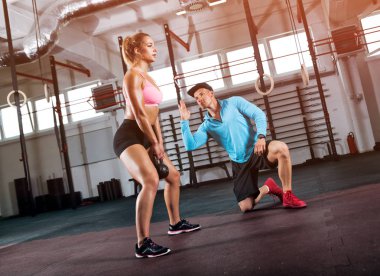 Uygun kadın kettlebell ve yardımı salonunda antrenörü ile ağız kavgası yapıyor