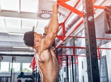 Pull ups egzersiz yaparak kaslı vücut geliştirmeci üzerinde bar salonunda