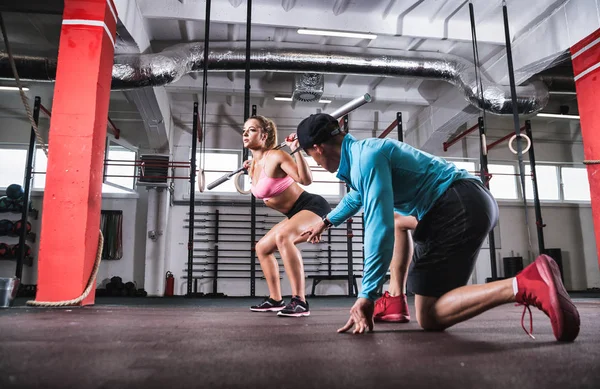 Fit vrouw doen halter kraakactie oefening met hulp van trainer bij gym — Stockfoto