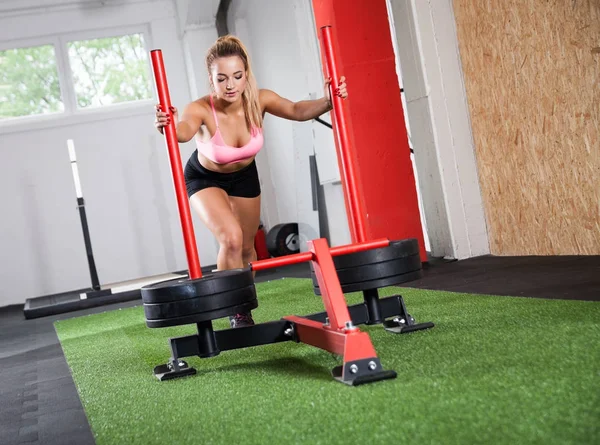 Fitness girl pushing sled at gym, cross exercise with equipment — Stock Photo, Image