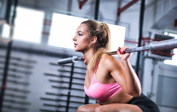 Muscular girl doing squats with barbell at gym, close up portrait — Stock Photo, Image