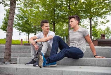 Şehirdeki merdivenlerde oturan ve konuşurken, b iki arkadaş casual giyim