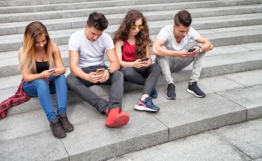 Arkadaş birlikte telefonlarını kullanarak oturma grubu