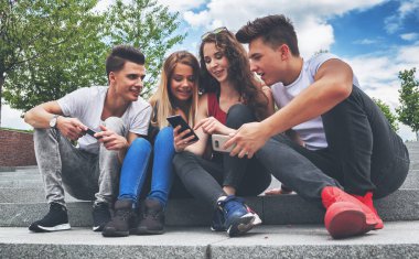 Arkadaş birlikte telefonlarını kullanarak oturma grubu