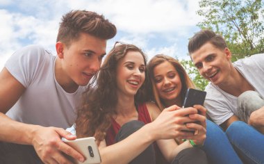 Arkadaş birlikte telefonlarını kullanarak oturma grubu
