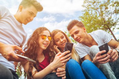 Arkadaş birlikte telefonlarını kullanarak oturma grubu