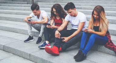 Arkadaş birlikte telefonlarını kullanarak oturma grubu