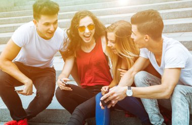 Grup oturan arkadaşıyla birlikte telefon kullanarak ve gülüyor