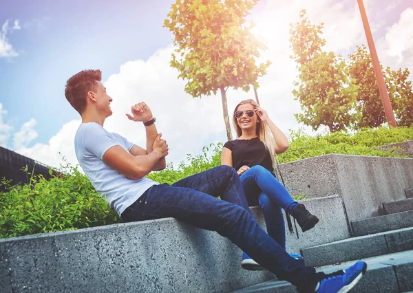 Pareja joven sentada al aire libre y riendo, concepto de felicidad — Foto de Stock