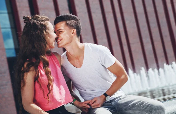 Pareja joven sentada al aire libre y dando beso, concepto de felicidad —  Fotos de Stock