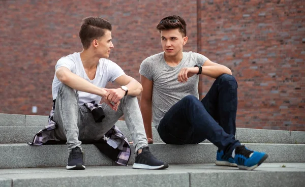 Dwóch przyjaciół dorywczo nosić siedząc na schodach, w mieście, w rozmowie, najlepszy przyjaciel — Zdjęcie stockowe