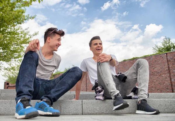 Два друга сидят на лестнице в городе и смеются, концепция лучшего друга — стоковое фото