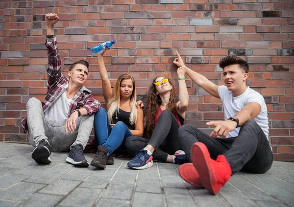 Heureux groupe d'amis assis dans la rue mettre les mains en l'air — Photo