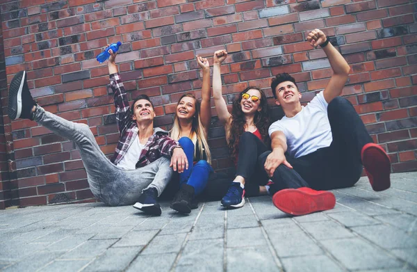 Happy group of friends sitting on street put hands up — Stock Photo, Image