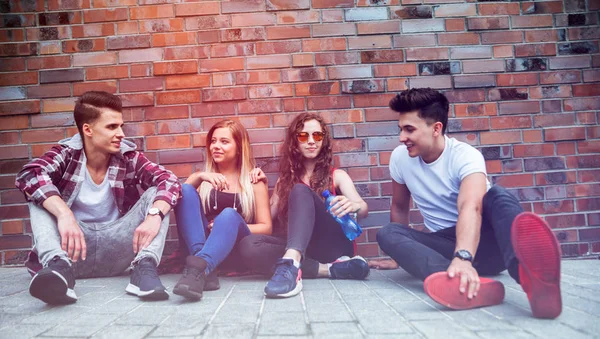 Groep jonge vrienden op straat zitten en praten — Stockfoto
