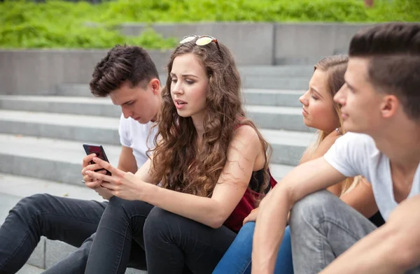 Grupa przyjaciół, siedzi ze sobą za pomocą swoich telefonów — Zdjęcie stockowe