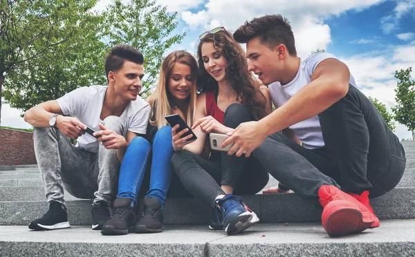 Groupe d'amis assis ensemble en utilisant leurs téléphones — Photo