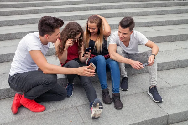 Groupe d'amis assis ensemble en utilisant leurs téléphones — Photo