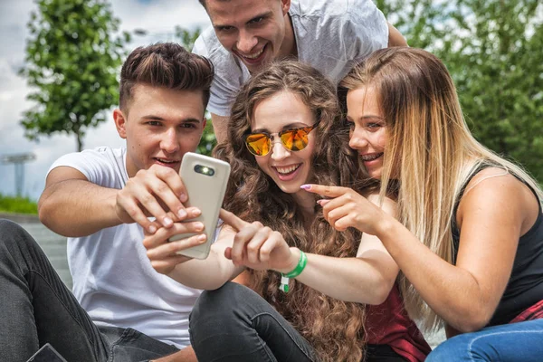 Group of friends sitting together using phone and laughing — Stock Photo, Image