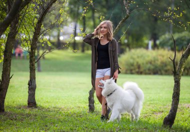 Genç kız yürüyüş samoyed köpek parkı