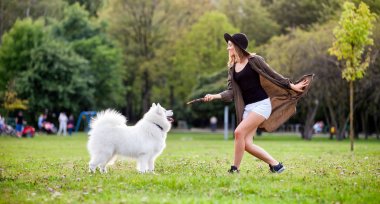 Çimenlerin üzerinde açık oynayan köpek ile gülümseyen neşeli kız