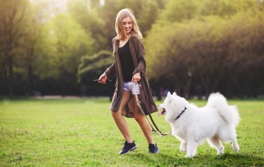 Güzel kız yürüyüş sırasında açık Samoyed köpekle oynamayı