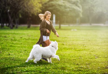 Güzel kız yürüyüş sırasında açık Samoyed köpekle oynamayı