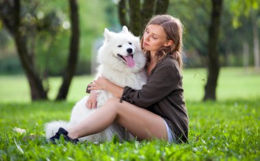 Güzel kız köpeğini parkta samoyed sarılma