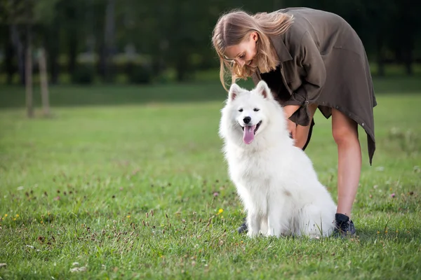 Hübsches junges Mädchen mit ihrem samoy Hund im Park — Stockfoto