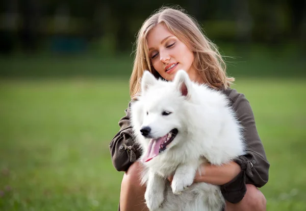 Ziemlich glückliches Mädchen, das mit ihrem Hund im Park spielt, samoyed — Stockfoto