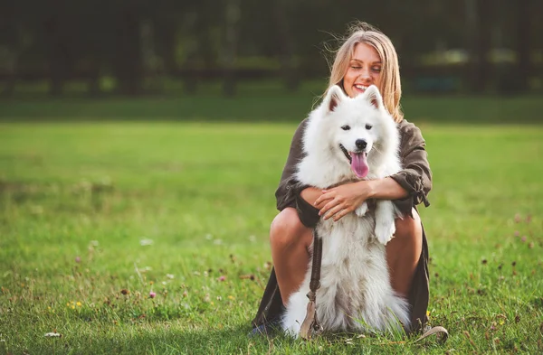 Mooi meisje speelt met haar hond in het park, Samojeed — Stockfoto