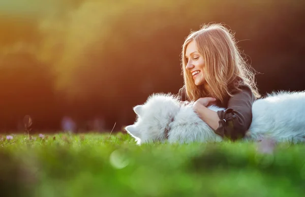 Pretty girl playing with dog on grass at the park — Stock Photo, Image