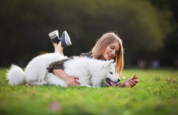 Mooi meisje met hond op gras in het park spelen — Stockfoto