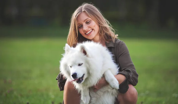 Porträtt av leende flicka med hennes hund på park utomhus, samojed — Stockfoto