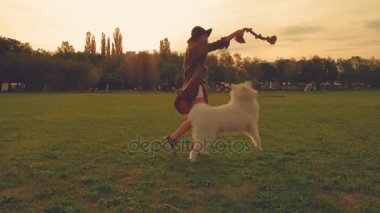 Genç kadın günbatımında samoyed köpek parkta oynarken