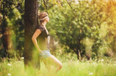 Hippi kız çayır üzerinde ağaç altında yaz gününde ayakta