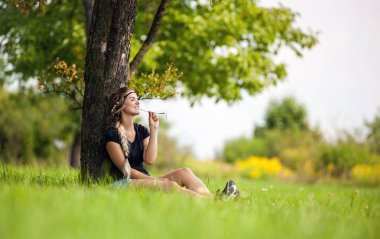 Ağacın altında oturan çayır üzerinde yaz gününde hippi kız