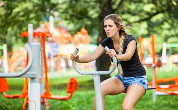 Mulher se exercitando no ginásio ao ar livre, equipamentos de playground — Fotografia de Stock