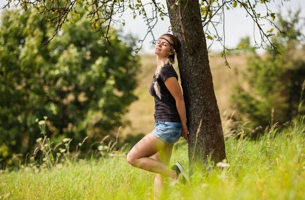 Fille détendue debout sous l'arbre sur la prairie le jour de l'été — Photo