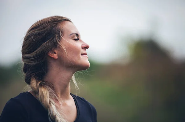 Schöne Frau mit Zopf im Freien, die in die Sonne starrt und lächelt — Stockfoto