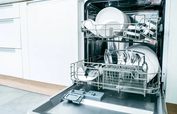 Відкрита посудомийна машина з чистим посудом на білій кухні — стокове фото