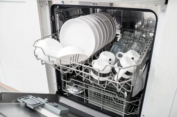 Открытая посудомоечная машина с чистой посудой на белой кухне — стоковое фото
