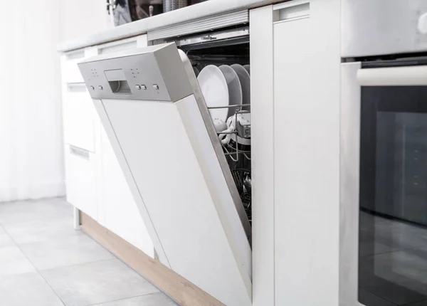Máquina de lavar louça aberta com pratos limpos na cozinha branca — Fotografia de Stock