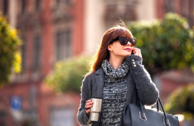 Şehir içinde cep telefonu konuşurken kahve fincanı kadınla