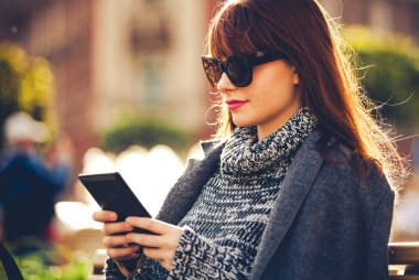 Şehirde, kentsel sahne oturan tablet veya ebook reader'ı kullanarak güzel kadın