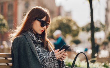 Şehirde, kentsel sahne oturan tablet veya ebook reader'ı kullanarak güzel kadın