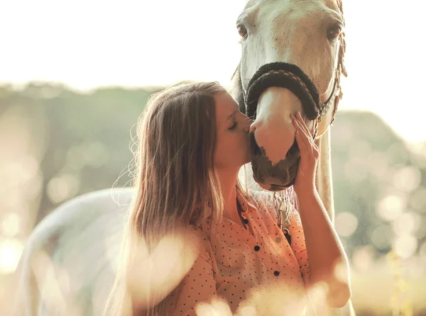 Mujer besando a su caballo al atardecer, escena al aire libre — Foto de Stock