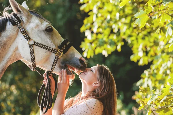 Mujer besando a su caballo al atardecer, escena al aire libre — Foto de Stock