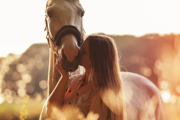 Mujer besando a su caballo al atardecer, escena al aire libre — Foto de Stock
