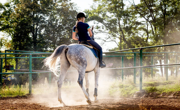 Woman riding a horse in dust on paddock